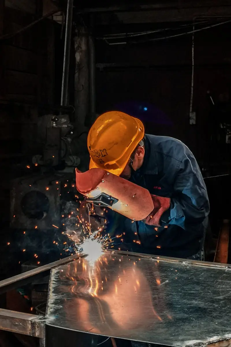 A welder wearing protective gear works on metal in an industrial workshop, surrounded by sparks.